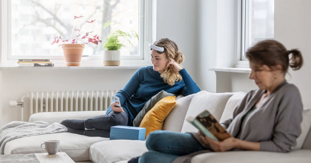 Two women sitting on sofa treating their MDD with tDCS devices